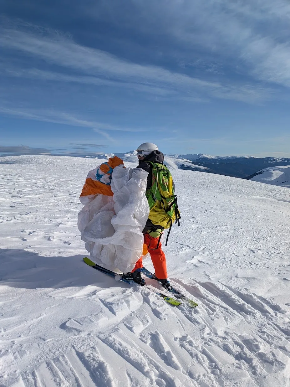 En la cima con los esquís, recogiendo la vela, con la panorámica nevada del Berguedà delante