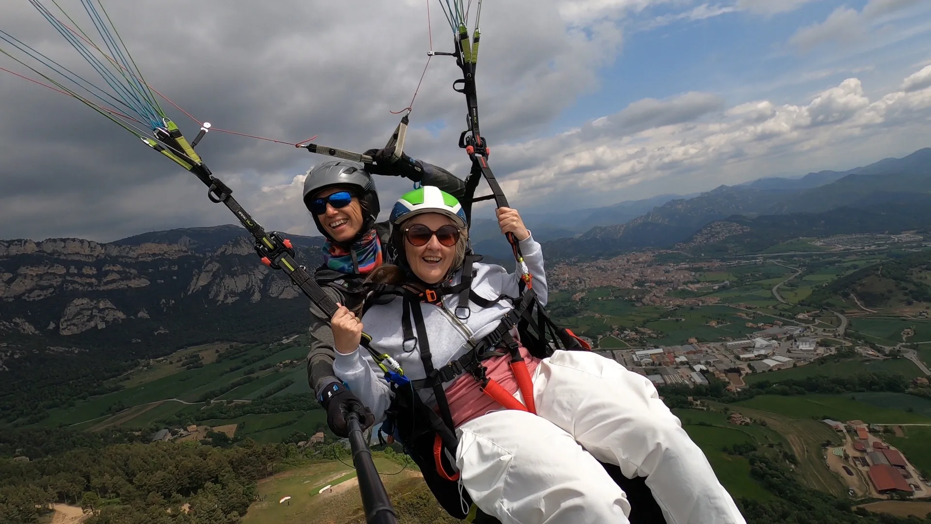 Pasajera y piloto sonrientes en un vuelo de montaña, con Berga y los farallones a los pies