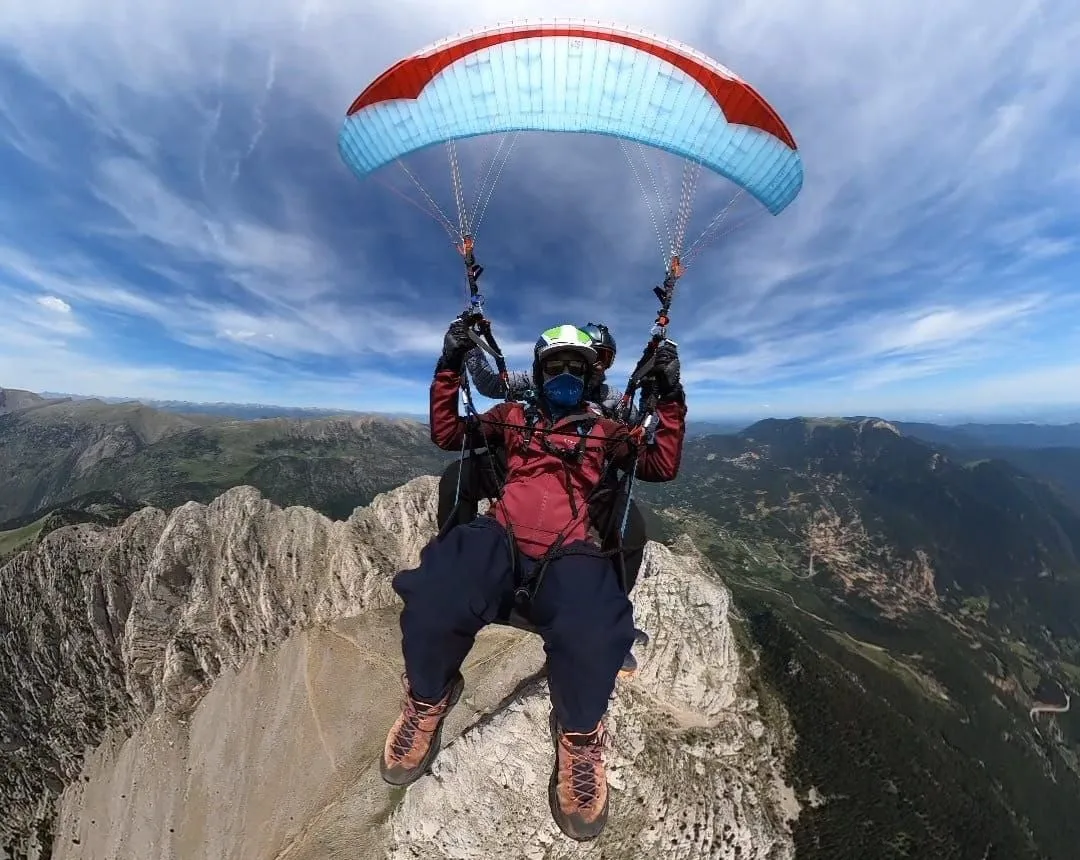 Biplaza en vuelo sobre las paredes de roca, con la vela encima